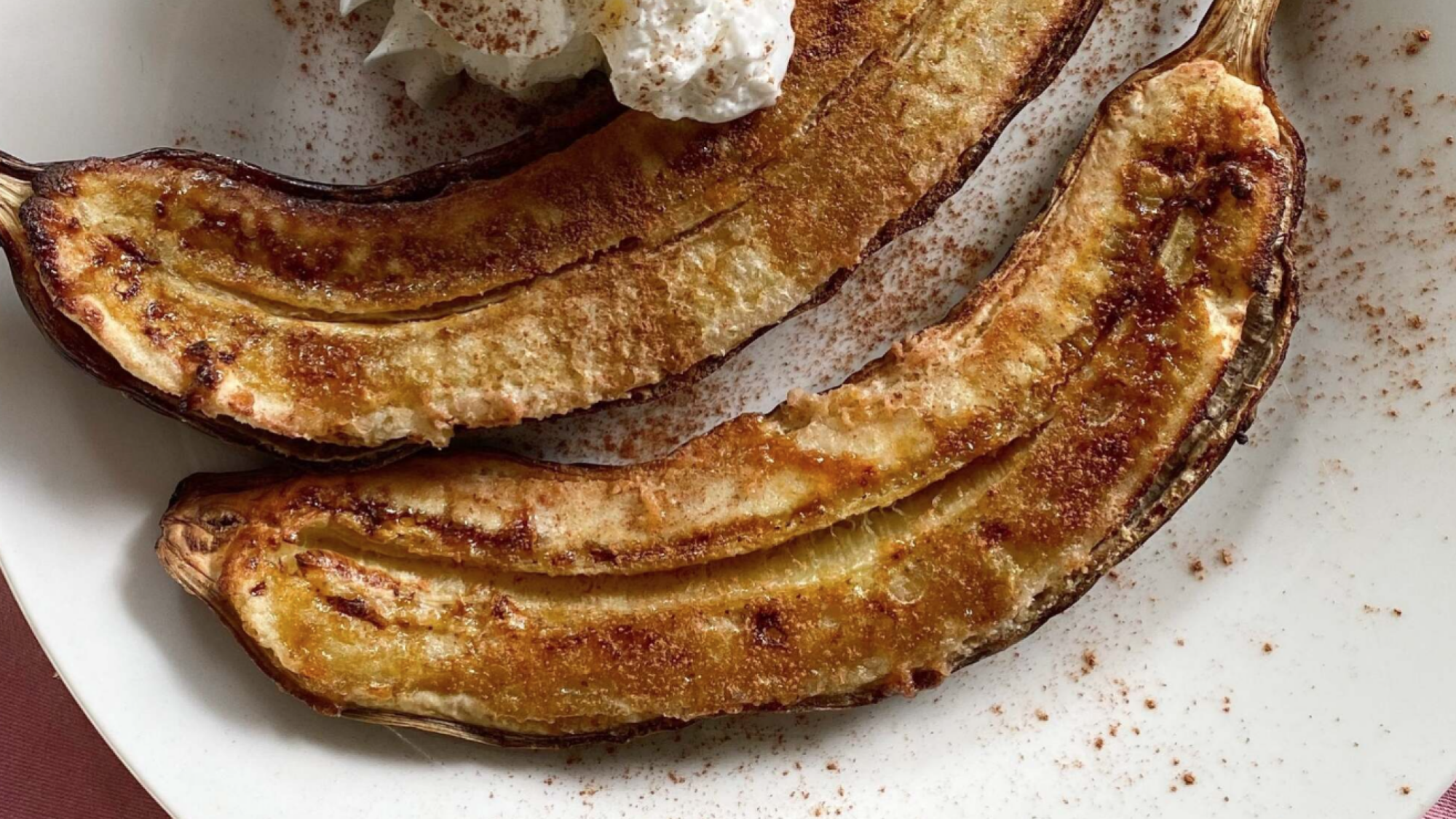 Air fried banana split in half and on a plate.